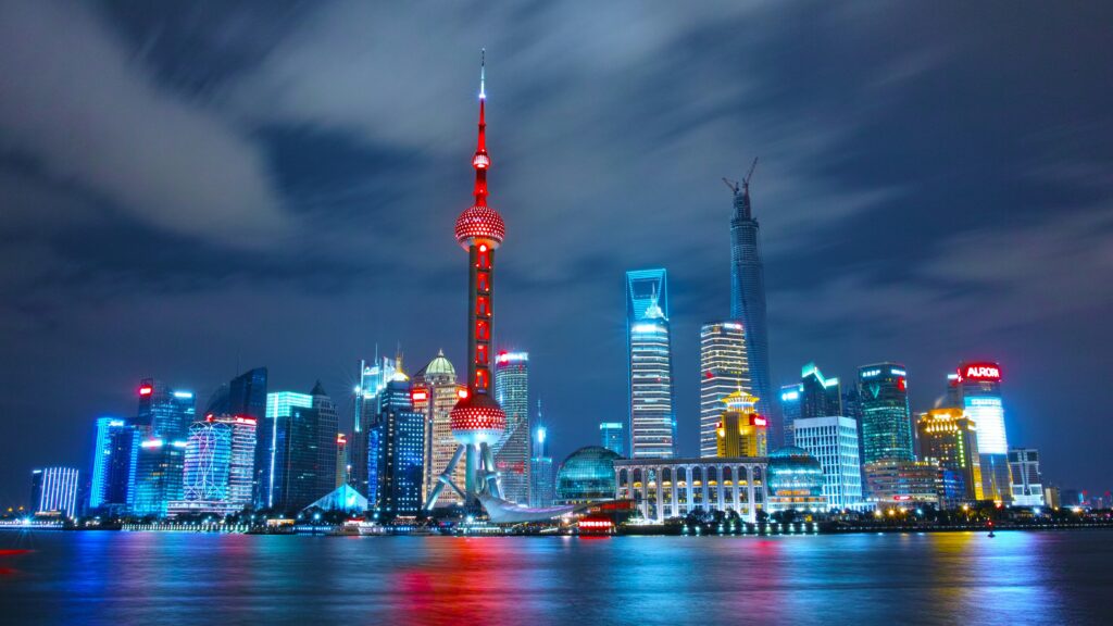 Shanghai skyline at night with Oriental Pearl Tower illuminated in red and surrounding skyscrapers.