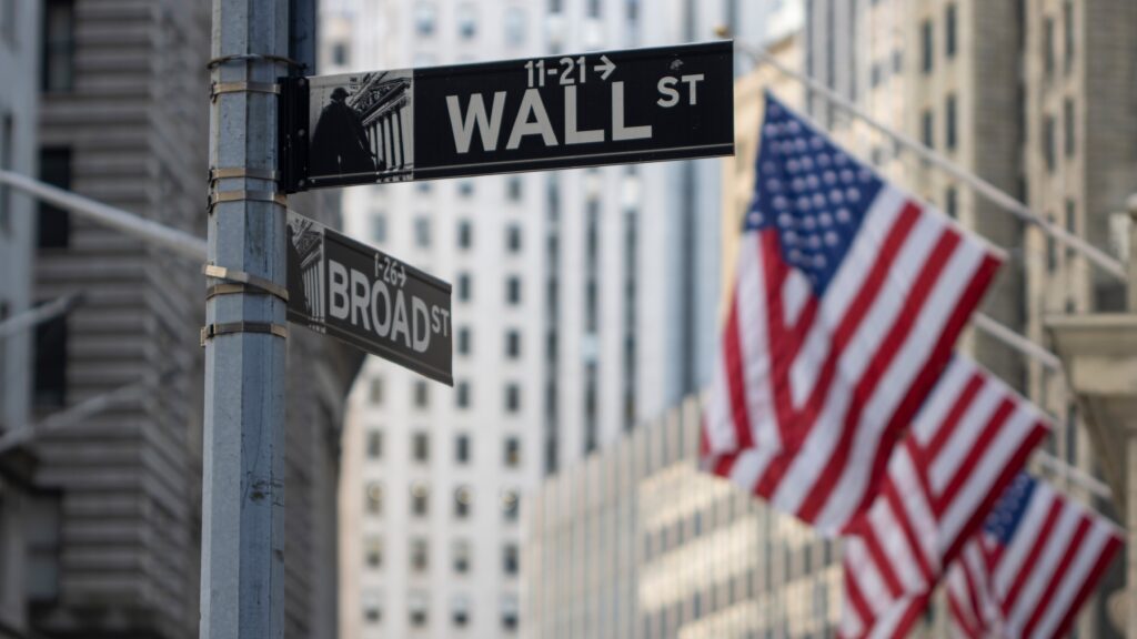 Wall Street and Broad Street signs with American flags in the background, symbolizing financial markets. The image accompanies an article on VT Markets titled 'Wall Street sees declines as treasury yields rise' discussing the impact of rising treasury yields on the market and upcoming US PCE inflation data.