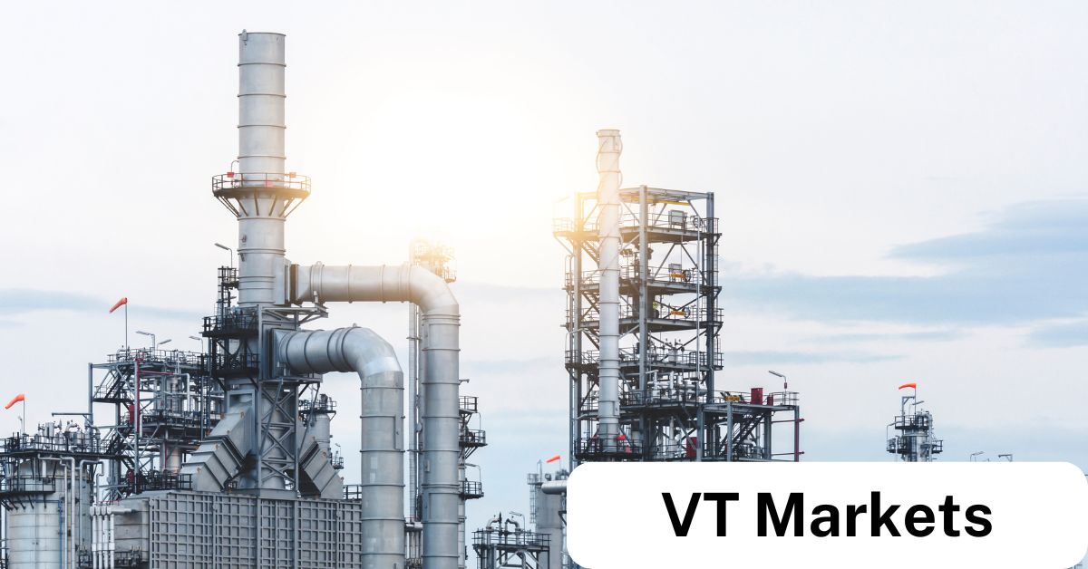 An industrial refinery complex with towering chimneys and pipelines against a clear sky, symbolising global energy markets and trading opportunities with VT Markets.